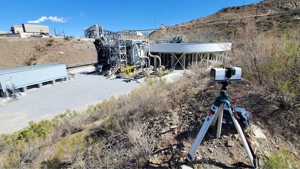 Artec Ray II on a tripod scanning a surface processing plant from a hillside above the site